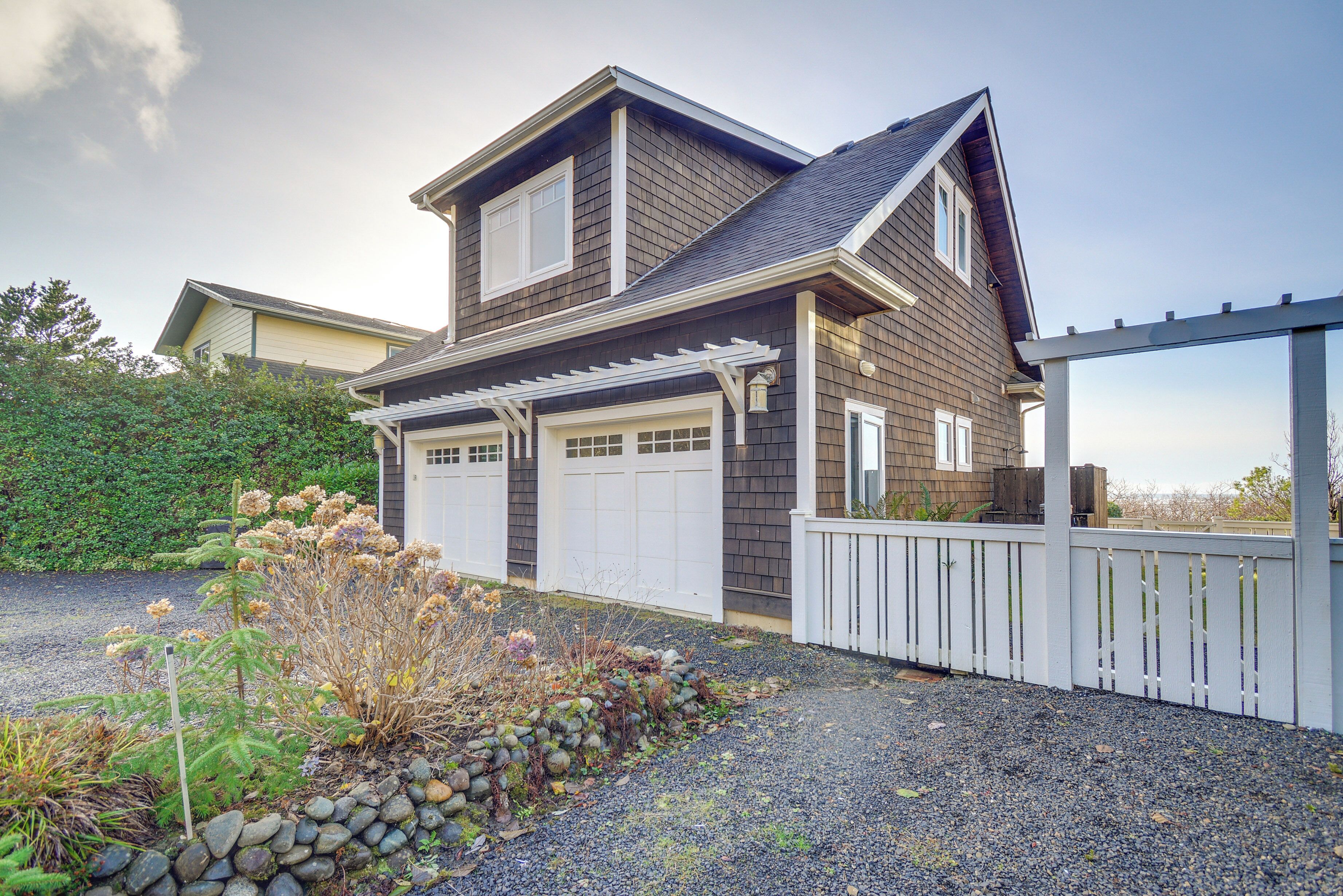 A two-story house with a garage, a covered porch, and a fenced driveway.