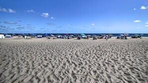 Una playa arenosa con sombrillas y sillas de playa.