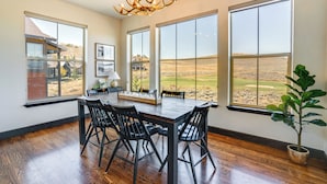 A dining area with a wooden table and chairs, large windows with a view of a golf course, and a chandelier. - Half-mi to Skiing: Gorgeous Granby Ranch Home! (Granby)