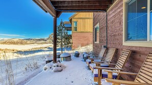 A covered outdoor seating area with wooden benches and a view of a building with large windows. - Half-mi to Skiing: Gorgeous Granby Ranch Home! (Granby)