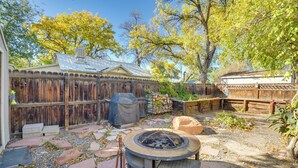 Un jardin avec un foyer, un chemin de pierre, une clôture en bois et un espace barbecue couvert.