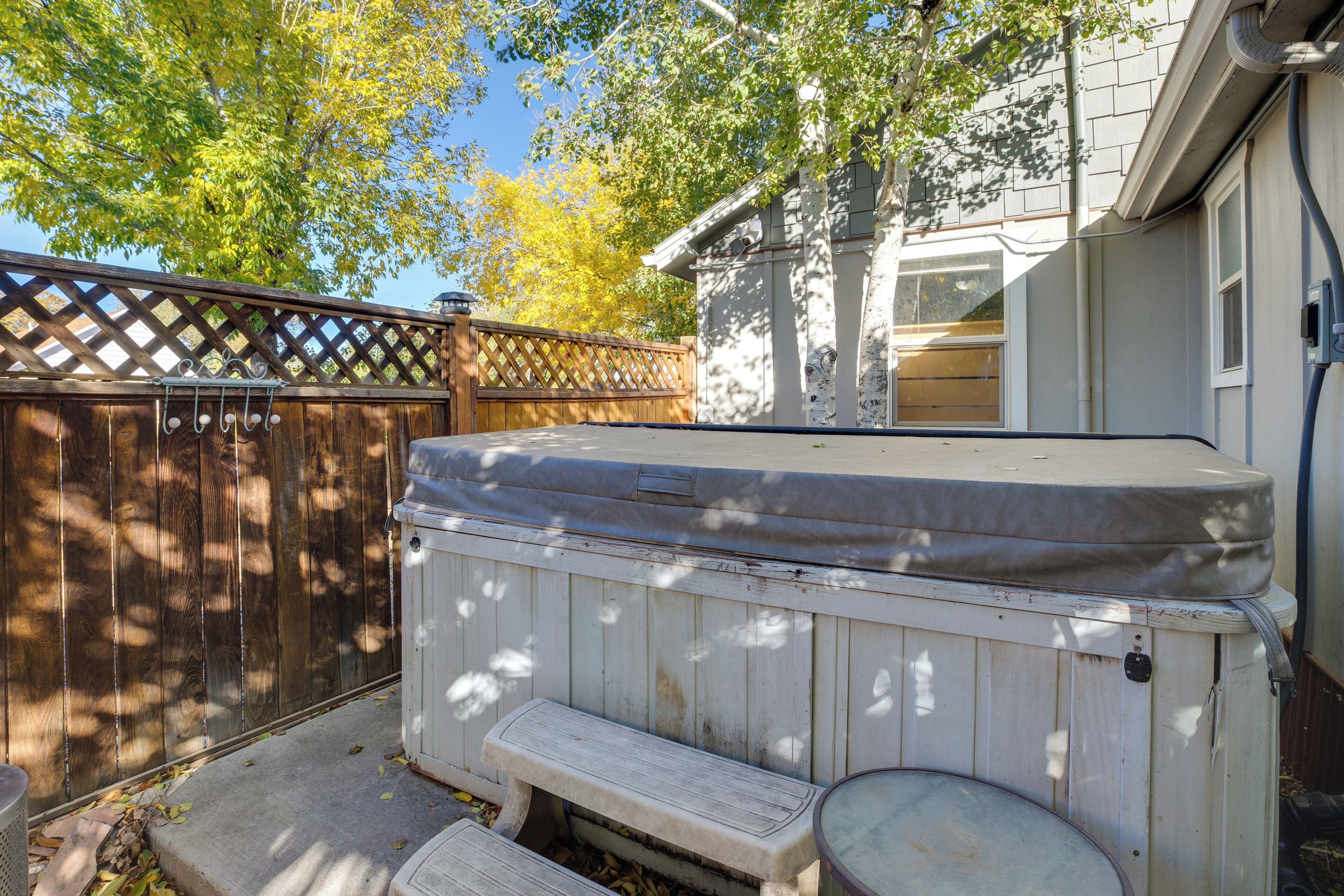 A hot tub with a wooden bench and a wooden fence in a backyard.