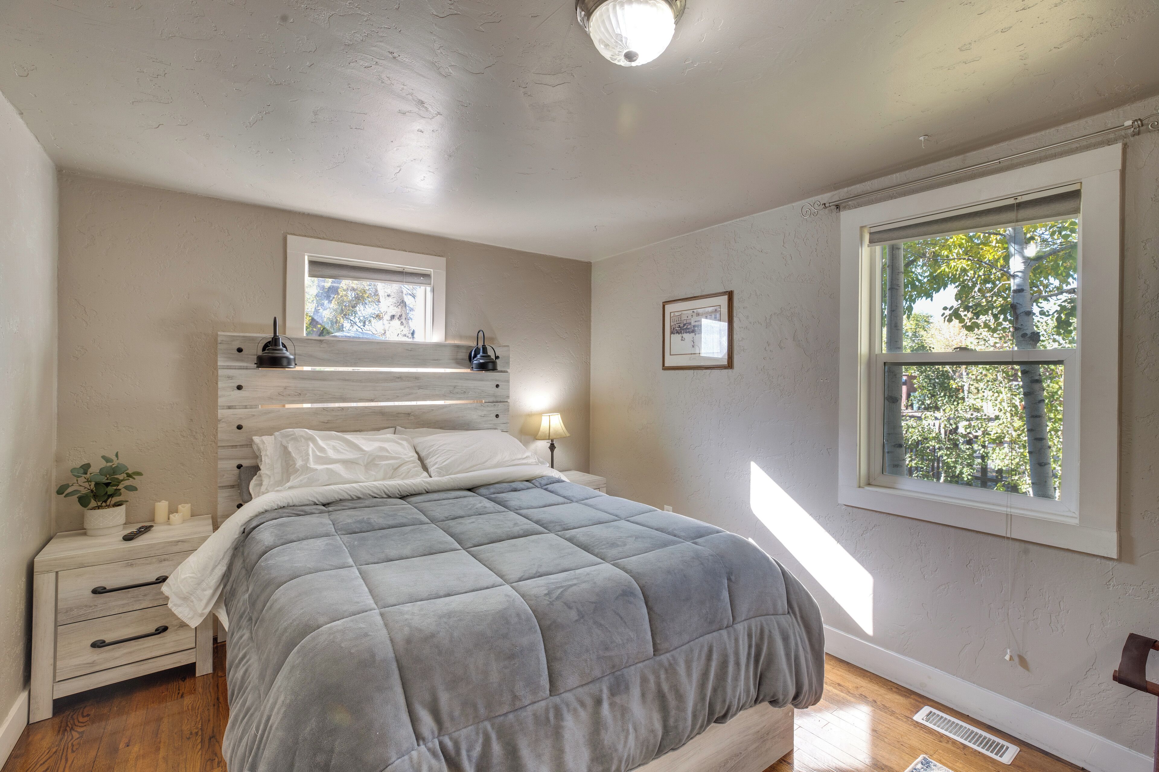 Une chambre à coucher avec un lit, des tables de chevet, une fenêtre et un luminaire au plafond.