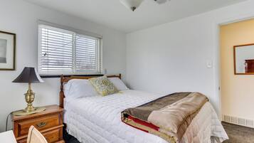 A bedroom with a bed, bedside table, lamp, and window.