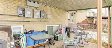 Un espacio al aire libre techado con una mesa, sillas, un muro de ladrillo y cajas eléctricas.