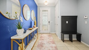 A hallway with a blue wall, a white console table with a vase of flowers, and a bench. - 4 Mi to Dtwn: Home w/ Pool Access in Sanford (Sanford)