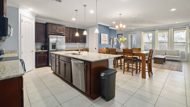 A modern kitchen with a central island, dark wooden cabinets, stainless steel appliances, and pendant lighting. - 4 Mi to Dtwn: Home w/ Pool Access in Sanford (Sanford)