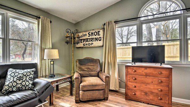 A living room with a leather armchair, a wooden dresser, a television, and a sign reading "Boston Shoe Repairing Shop". - Studio w/ Patio - Walk to Hikes, Sights & Bites (Aberdeen)