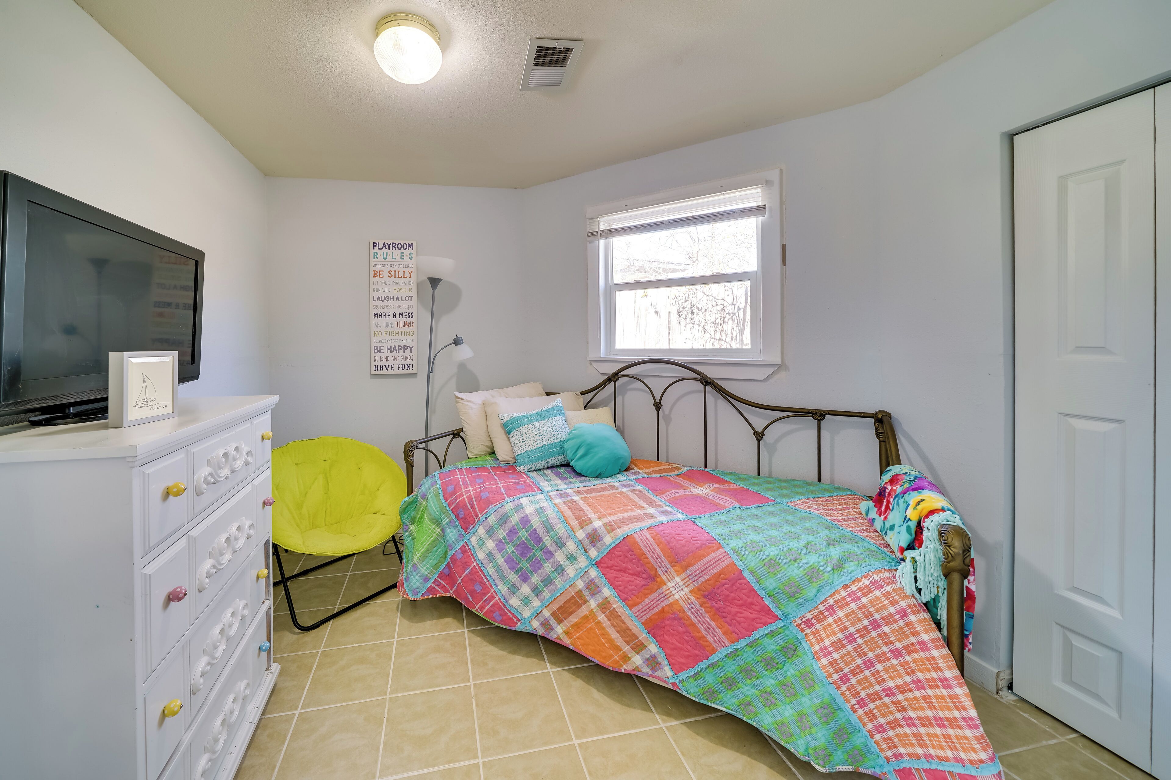 Une chambre à coucher avec un lit, une commode, une chaise, une fenêtre et une porte.