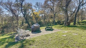 Un área de picnic con una mesa cubierta, dos sillas y un césped verde.