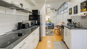 Une cuisine moderne avec des meubles blancs, une plaque de cuisson à induction noire et un réfrigérateur noir.
