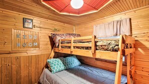 Dormitorio con literas, techo de madera, un cuadro en la pared y un cartel que dice 'KIDS ROOM'.