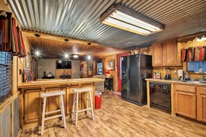 Eine rustikale Küche mit Holzsäulen, einer Bar mit Hockern, einem Kühlschrank und einem Geschirrspüler.