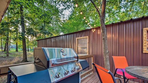 Un área de parrilla al aire libre con una terraza de madera, una mesa y sillas.