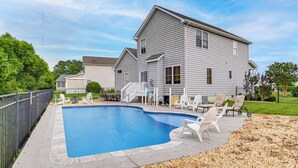 Une piscine résidentielle avec un patio couvert, entourée d’une clôture et d’une maison dotée d’une terrasse à l’avant.