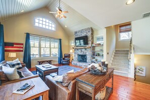 A spacious living room with a stone fireplace, leather furniture, and a wooden coffee table.