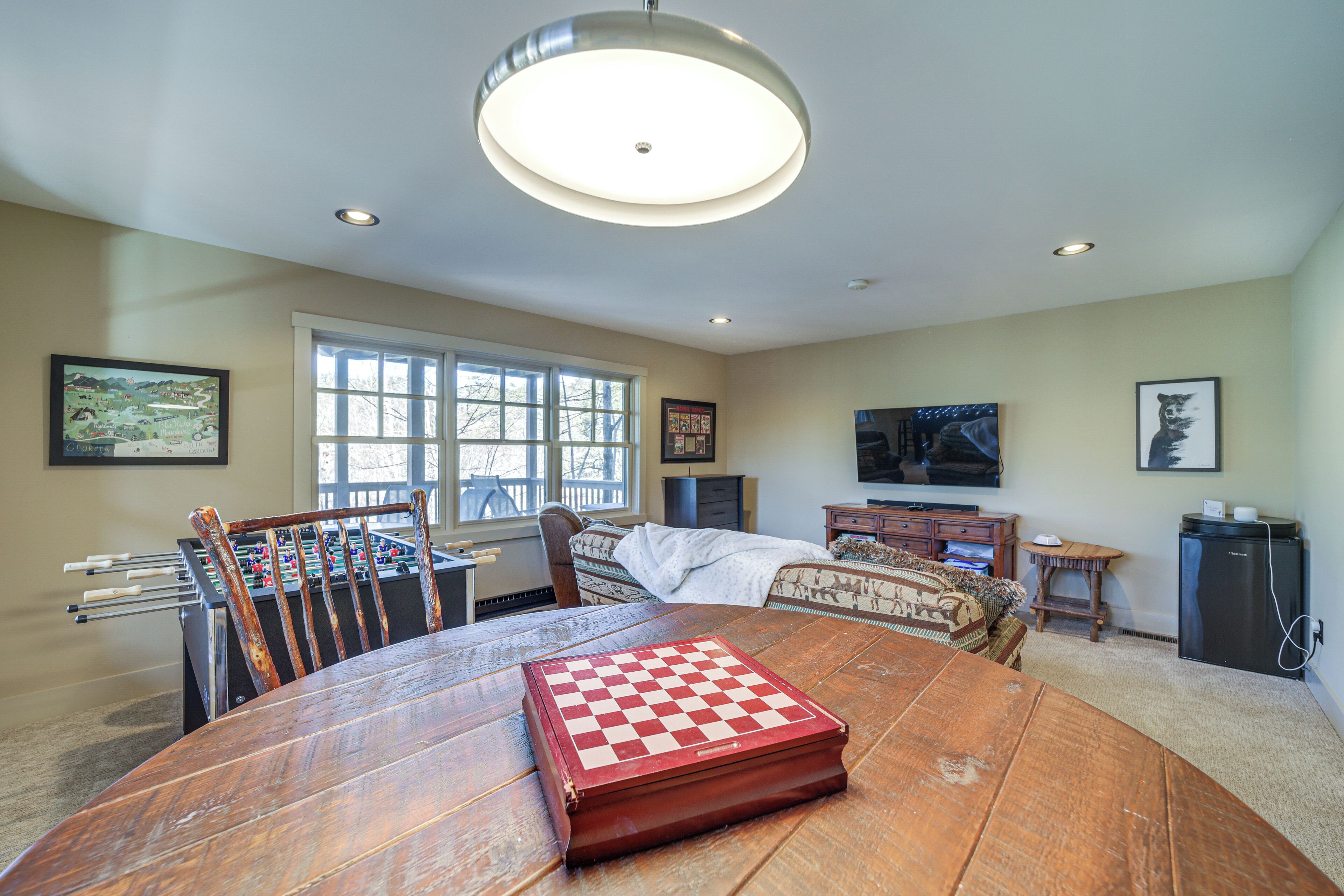 A cozy living room with a wooden table, a foosball table, and a television.
