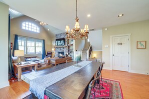 A spacious living area with a large wooden dining table, a fireplace, and a chandelier.
