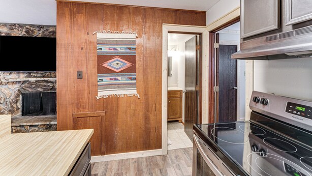 A kitchen with a built-in oven and a stone fireplace. - Shuttle to the Resort! Rustic Angel Fire Condo (Angel Fire)