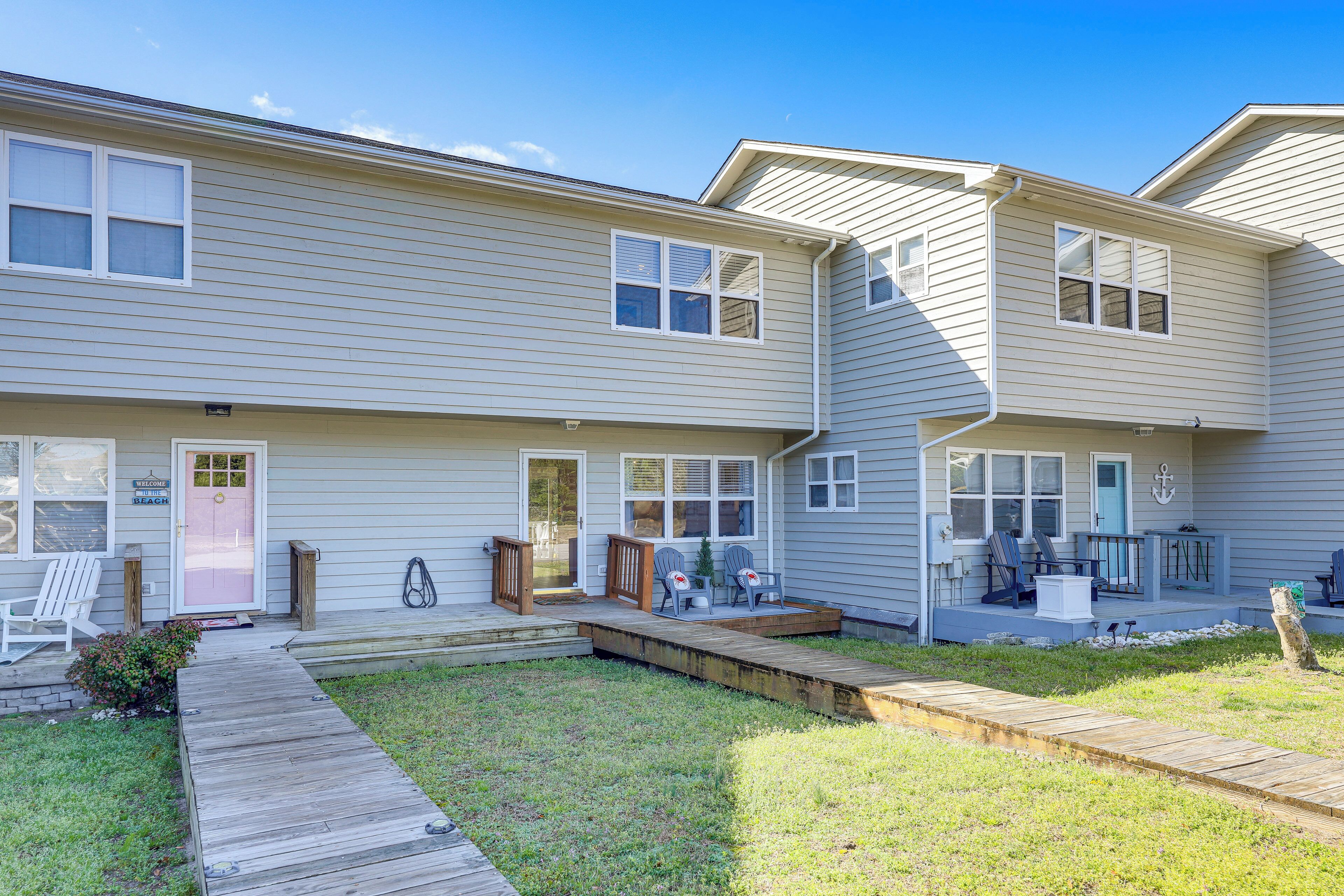 A two-story residential building with a front porch, a small deck, and a grassy yard.