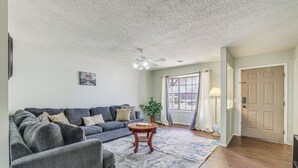 A living room with a gray sofa, a round wooden coffee table, and a ceiling fan.