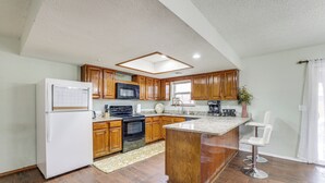 A modern kitchen with wooden cabinets, a central island, and a refrigerator.
