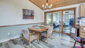 A dining area with a wooden table and chairs, a chandelier, and a large mirror reflecting the room. - Versatile Castle Rock Lake Home With Fire Pit! (Friendship)