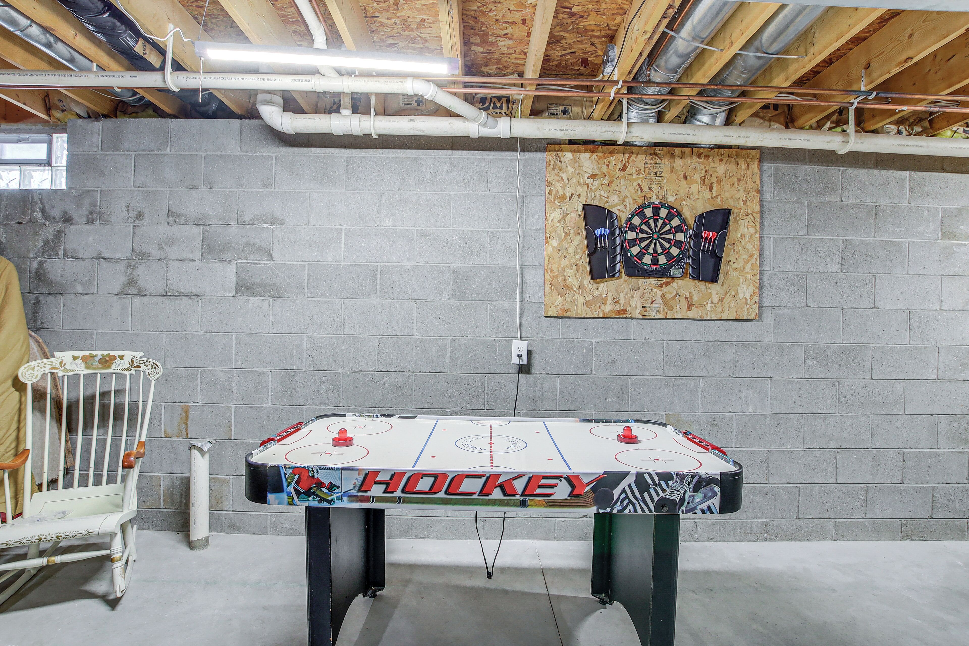 Una mesa de hockey de interior con un logo que dice 'HOCKEY', un dardo y una silla frente a una pared de ladrillo.
