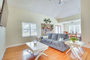 A spacious living room with hardwood flooring, a grey sofa, a white coffee table, and a dining area with a wooden table and chairs. - Secluded Mount Pleasant Home - 6 Mi to Beaches! (Mount Pleasant)