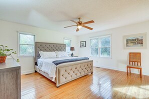 A bedroom with a bed, a ceiling fan, a chair, and large windows. - Secluded Mount Pleasant Home - 6 Mi to Beaches! (Mount Pleasant)