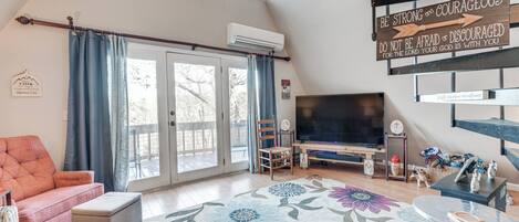 A cozy living room with a large TV, a sofa, a coffee table, and a decorative rug.