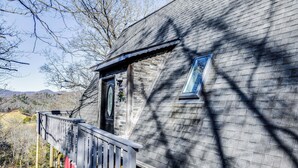 Une cabane rustique dotée d’une terrasse en bois et d’une grande fenêtre.