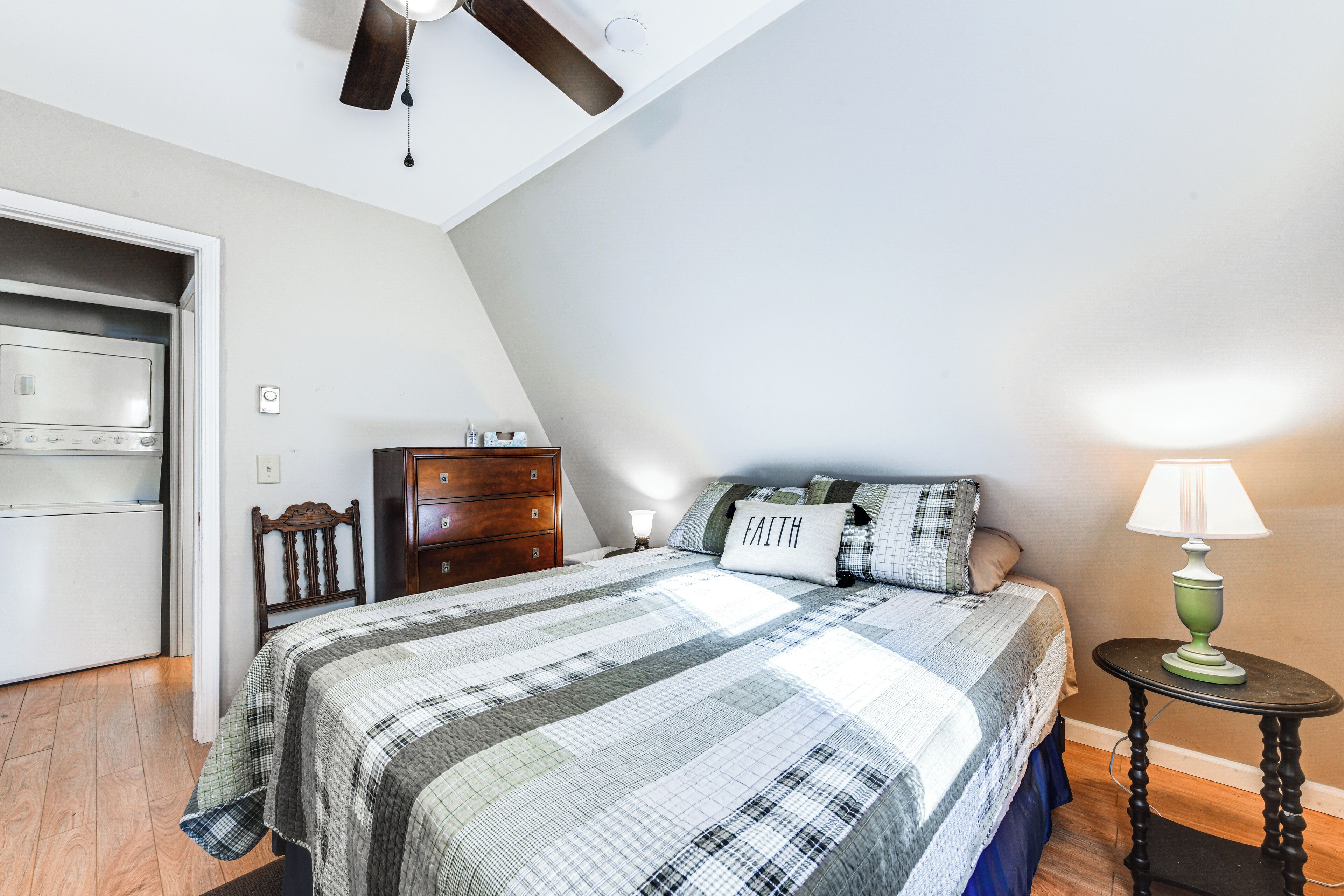 A bedroom with a bed, dresser, and a ceiling fan.
