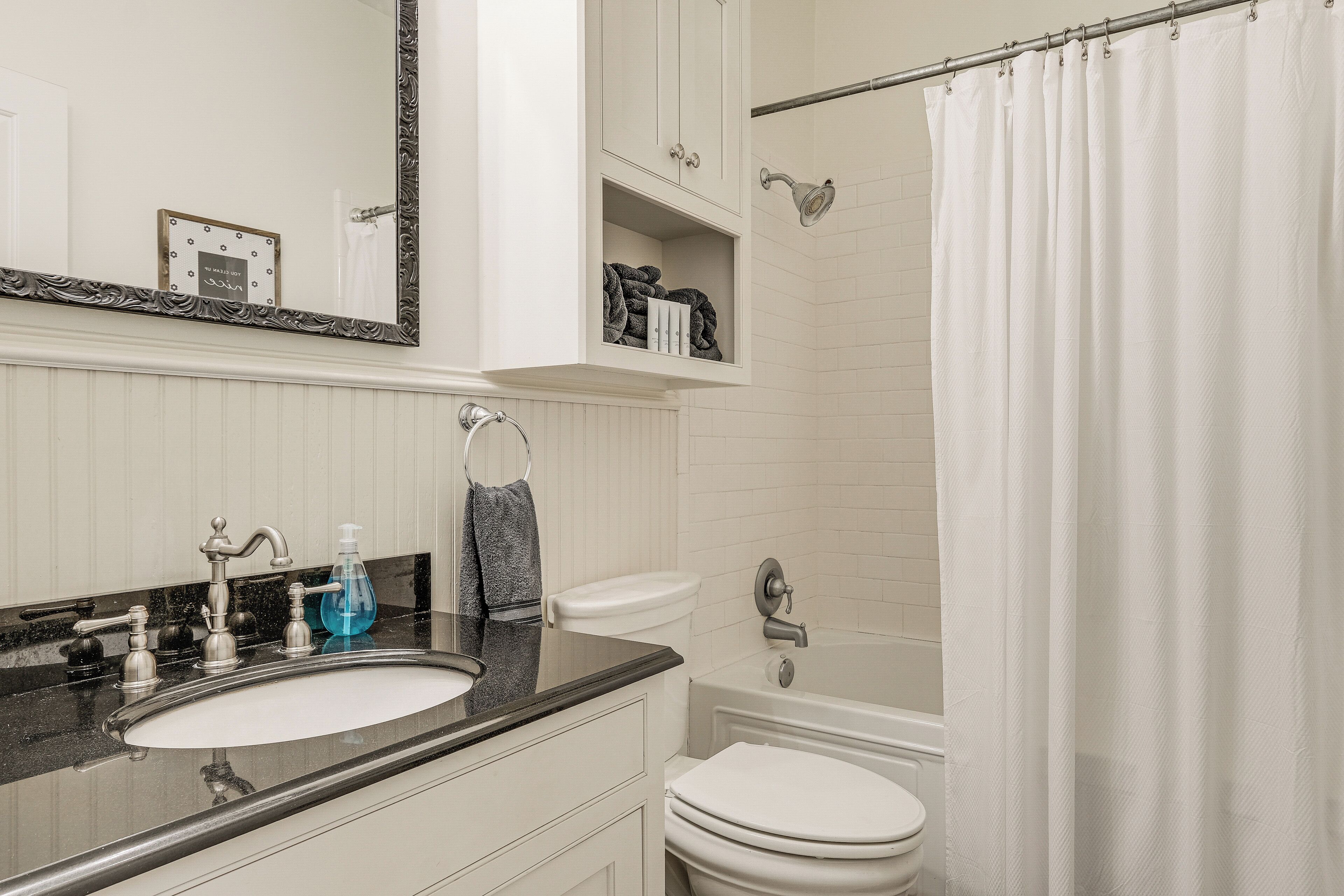 A bathroom with a sink, toilet, bathtub, and a shower curtain.