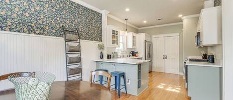 A modern kitchen with white cabinetry, a central island, and blue bar stools.