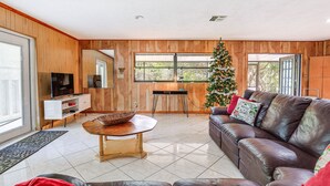 Una sala de estar moderna con un sofá de cuero, una mesa de comedor de madera y un árbol de Navidad.