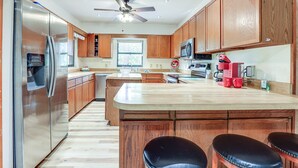 Una cocina moderna con armarios de madera, un refrigerador de acero inoxidable, un microondas y una cafetera.