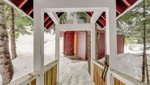 A snow-covered wooden pathway leading to a red building with a white roof. - Snoqualmie Pass Cabin w/ Deck: Walk to Ski Lift (Snoqualmie Pass)