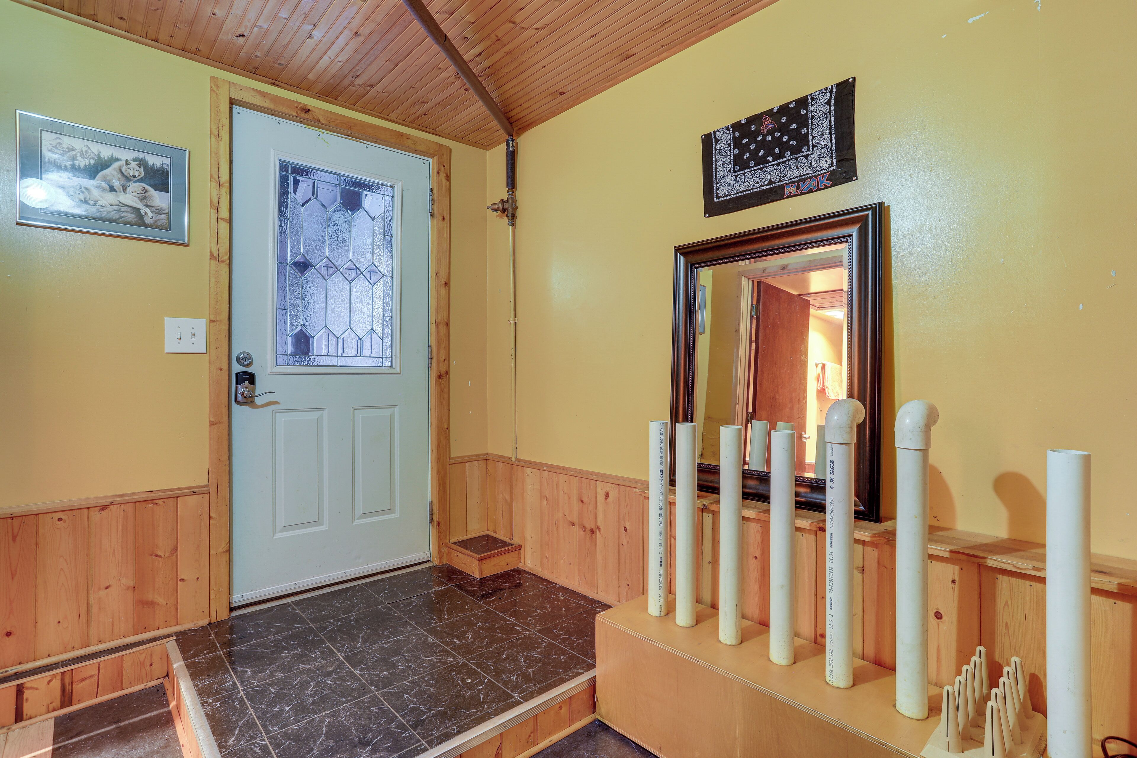 A wooden interior with a white door, a mirror, and a framed picture on the wall.