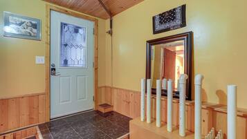 A wooden interior with a white door, a mirror, and a framed picture on the wall.