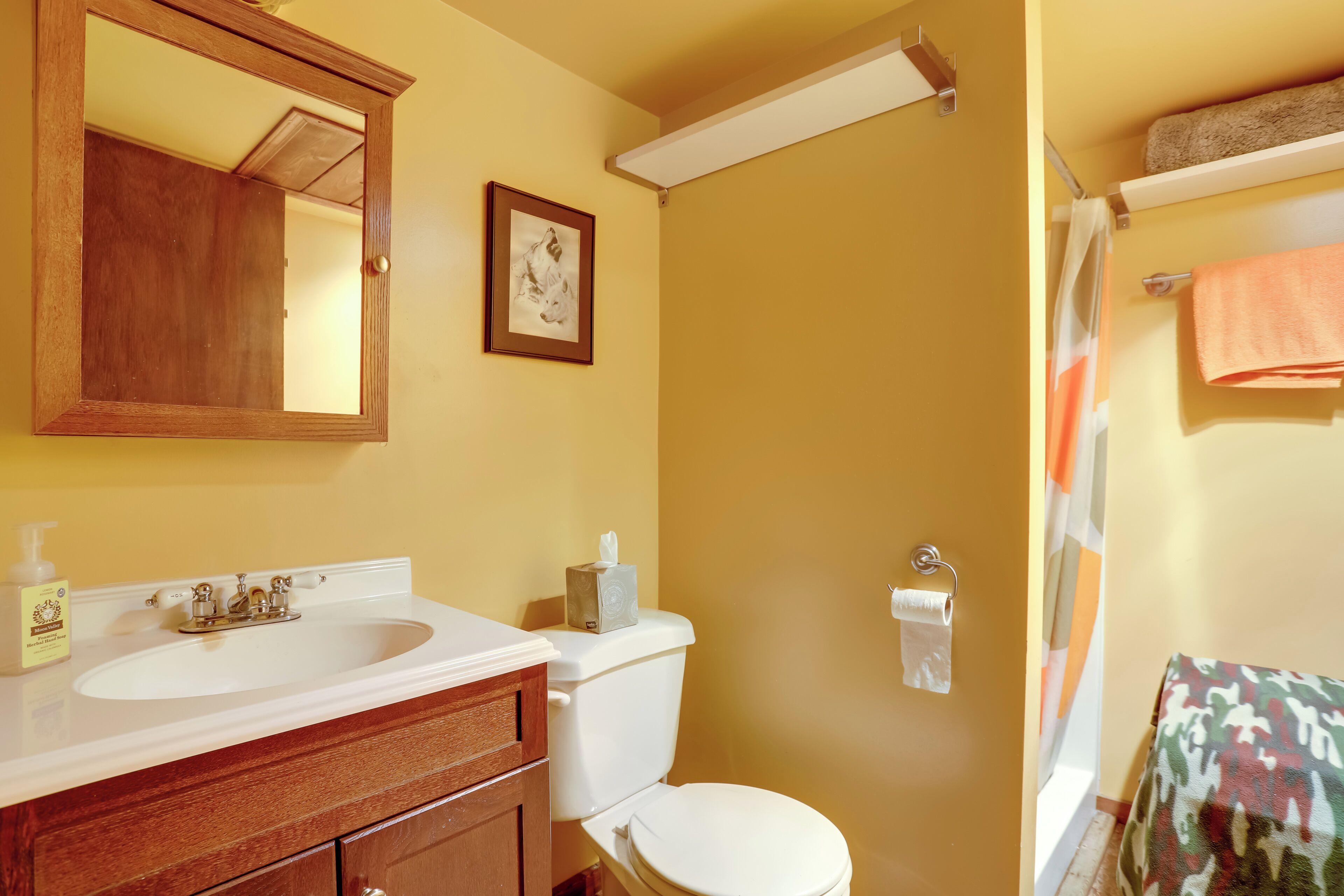 A bathroom with a wooden vanity, a sink, a toilet, and a shower curtain.
