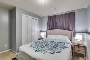 Une chambre à coucher comprenant un lit, des tables de chevet, une armoire et un luminaire au plafond.