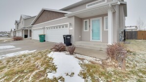 A two-story residential house with a garage, a front porch, and a small front yard with snow. - Pet-friendly North Dakota Escape w/ Fenced-in Yard (West Fargo)