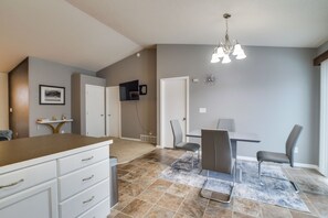 Une cuisine moderne avec des meubles blancs, un plan de travail marron et un coin repas comprenant une table et des chaises.