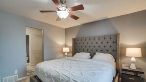 A bedroom with a large bed, two bedside tables with lamps, a ceiling fan, and a door leading to another room. - Pet-friendly North Dakota Escape w/ Fenced-in Yard (West Fargo)