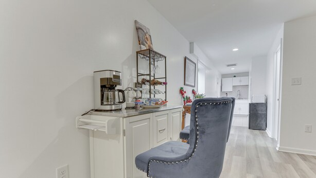 A modern kitchen with white cabinets, a coffee maker, and a chair. - Cozy Inwood Apartment: History, Hiking & Wine! (Inwood)