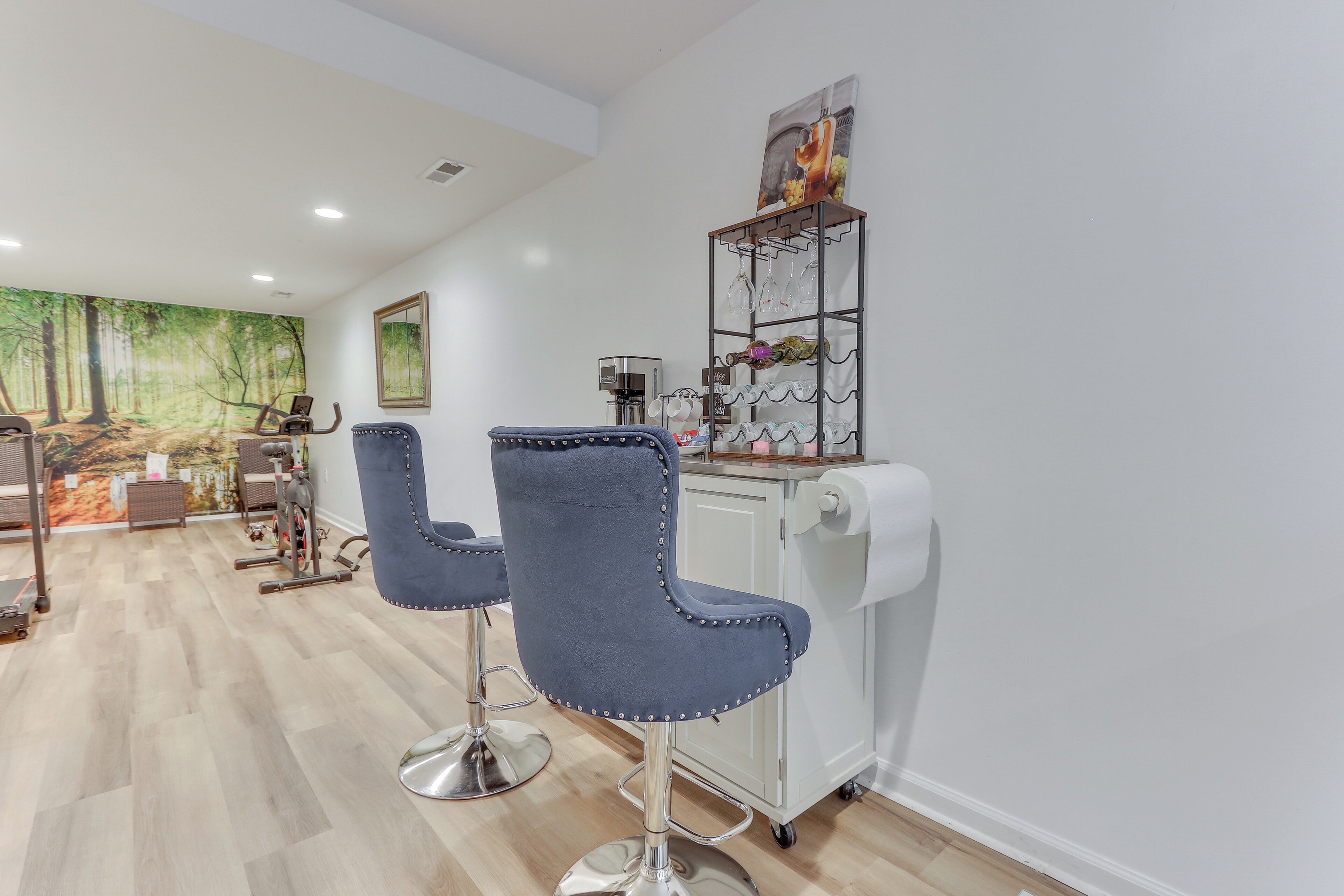 A modern bar area with two blue bar stools, a coffee machine, and a wine rack.