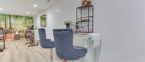 A modern bar area with two blue bar stools, a coffee machine, and a wine rack.