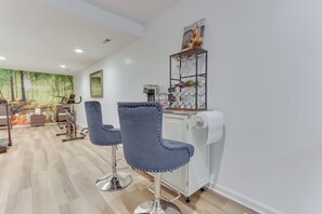 A modern bar area with two blue bar stools, a coffee machine, and a wine rack.