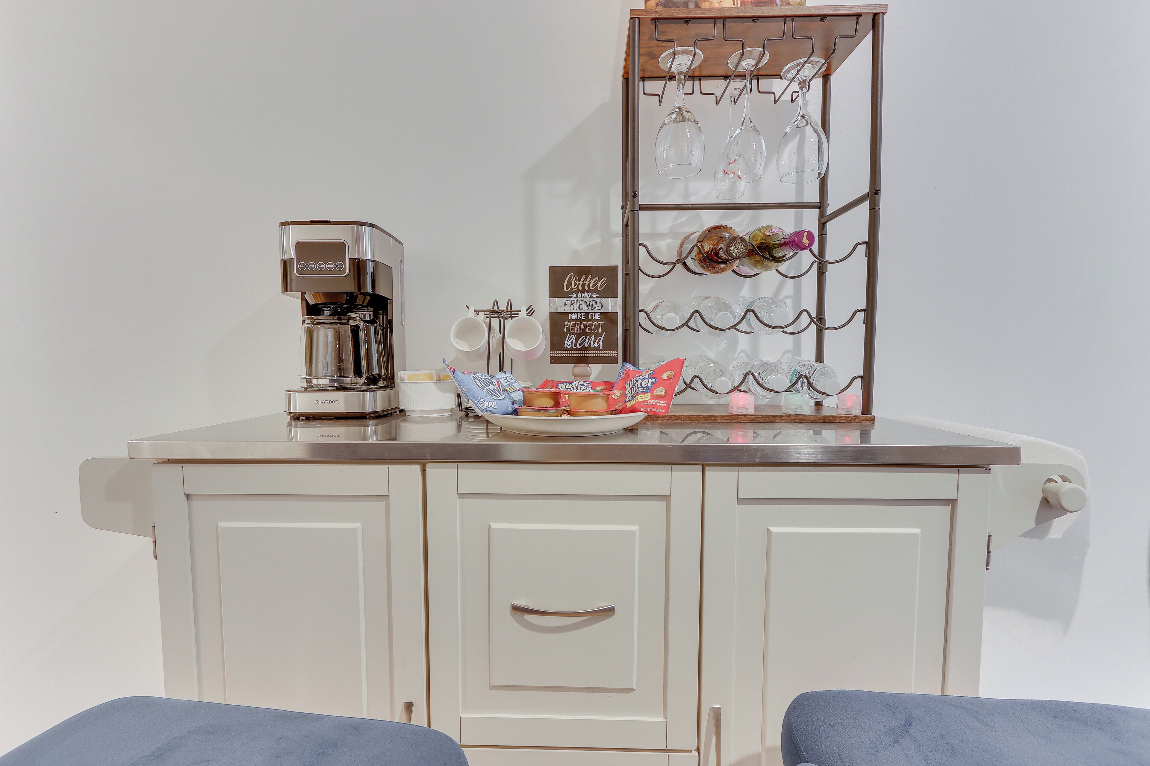 Eine Küchenzeile mit einer Kaffeemaschine, einem Weinkühlschrank aus Glas und einem Schild mit Kaffeemotiv.